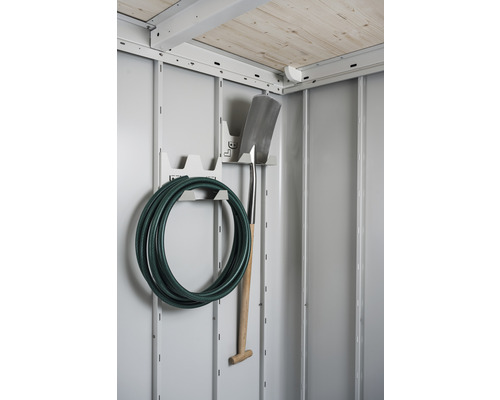 Trädgårdsslang och spade på ett verktygshållare i ett trädgårdsskjul