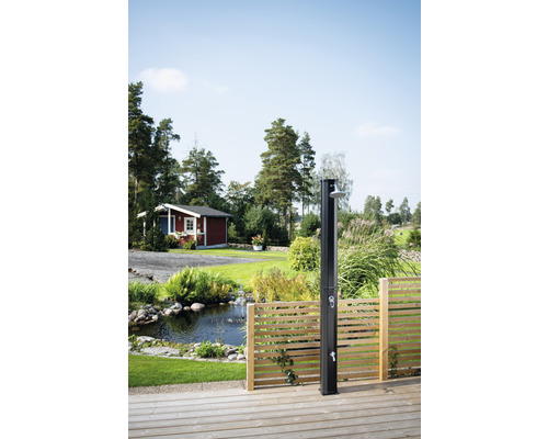 Utedusch på en träterrass med trädgårdsdamm och litet hus i bakgrunden
