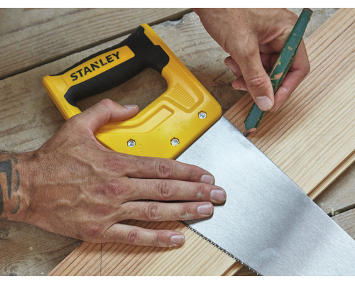 Man sågar träplanka med en handsåg från Stanley