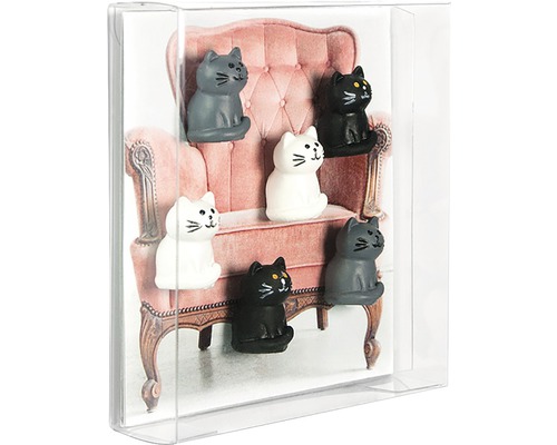 Dekorativa magneter i form av katter framför en bild av en stol