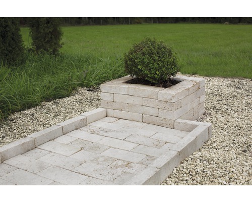 Trädgårdsscen med planteringslåda och gångväg av travertin