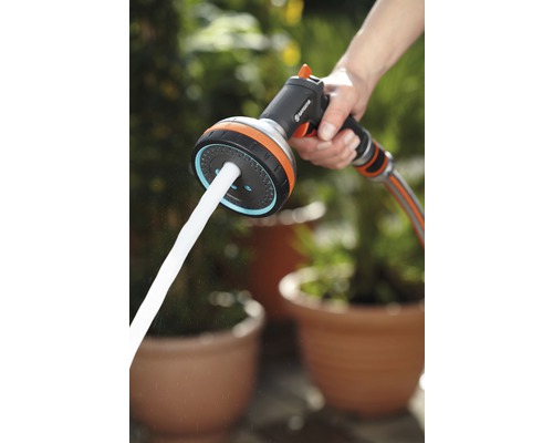 Trädgårdsslang sprutpistol med vattenstråle i handen.