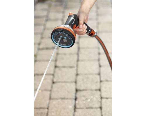 Trädgårdsslang med spruthuvud i handen