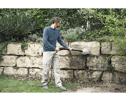 Man rengör stenmur med en borste och en högtryckstvätt.