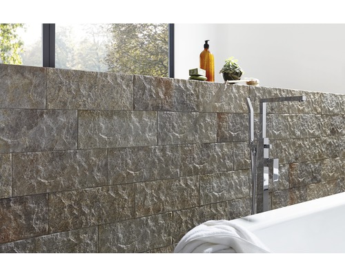 Badrumsdesign med naturstensvägg, badkar och armaturer