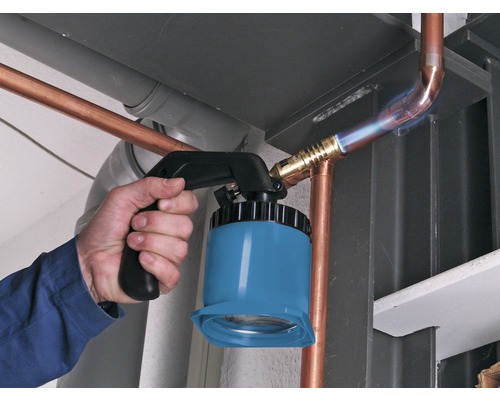 En hantverkare löder kopparrör med en lödlampa.