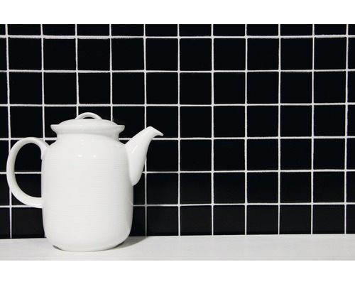 Tekanna av keramik framför ett kvadratiskt kakelmönster