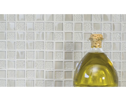 Glasmosaikplattor med en flaska olja i förgrunden