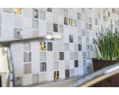 Närbild av en vägg med mosaikplattor och en krukväxt.