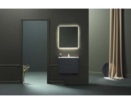 Modernt badrum med tvättställ, belyst spegel och dekorativa element för en stilfull atmosfär