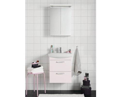 Badrum med tvättställsskåp, tvättställ och spegelskåp framför en vägg med kvadratiska plattor