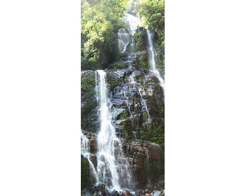 Landskap med ett vattenfall över stenar och vegetation