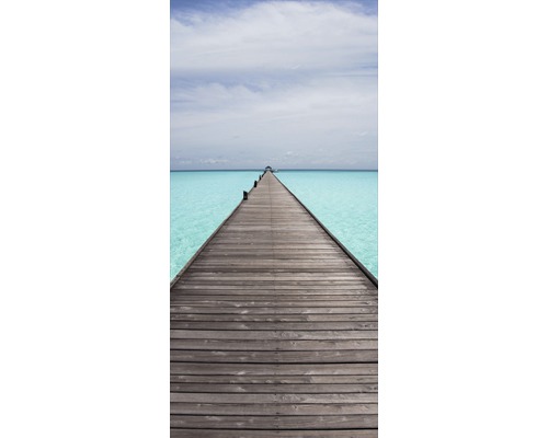 En lång träbrygga som leder ut i havet.