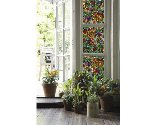 Dekorativ film med växtmönster på fönster, omgiven av krukväxter och en öppen dörr