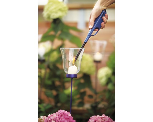 En hand tänder ett ljus i en lykta med en tändare.