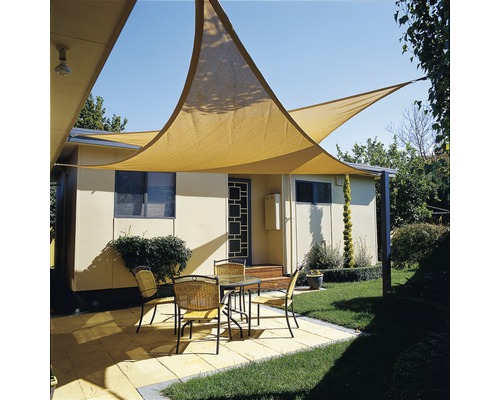 Uteplats med solsegel, bord och stolar framför ett hus