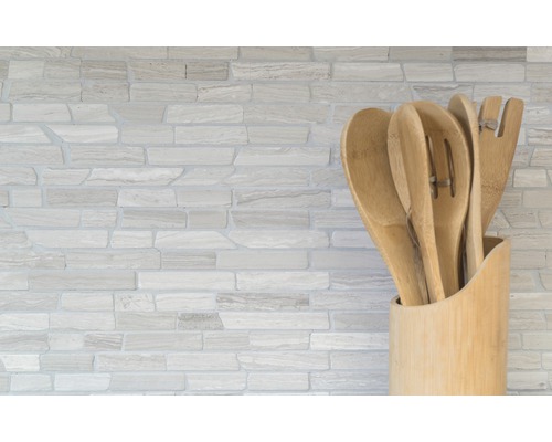 Köksredskap av trä i en hållare framför en stenvägg