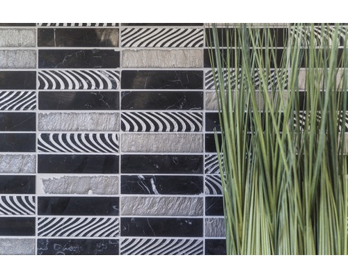 Dekorativa mosaikplattor i svart, vitt och grått bredvid prydnadsgräs