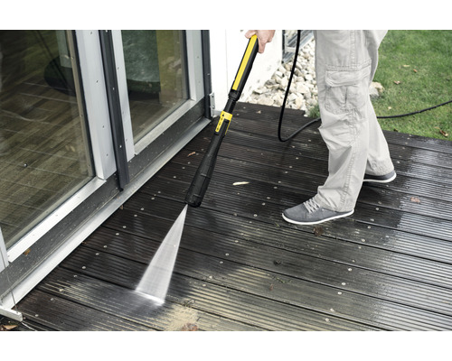 Person rengör trädäck med högtryckstvätt.