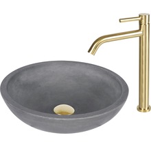 Grått tvättställ i betong med guldfärgad armatur