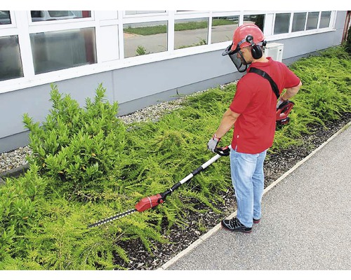 Man klipper häck med en batteridriven häcksax med teleskopskaft och skyddsutrustning