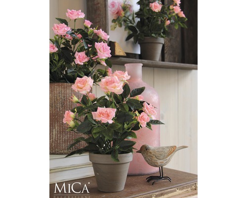 Dekorativa rosor i kruka på ett bord med en trädekoration i form av en fågel och en vas.