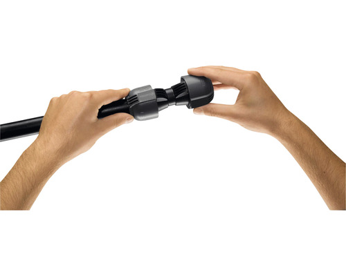 Två händer monterar en svart anslutning på ett svart rör.