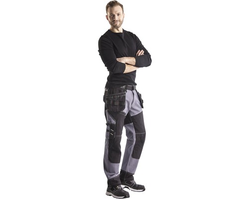 Man med arbetsbyxor, arbetsskor och långärmad tröja