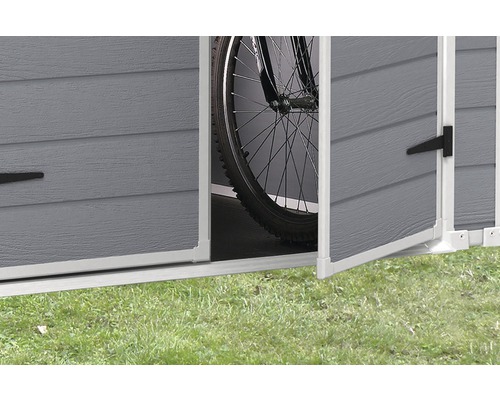 Detaljvy av ett öppet trädgårdsredskapsförråd med en cykel inuti.