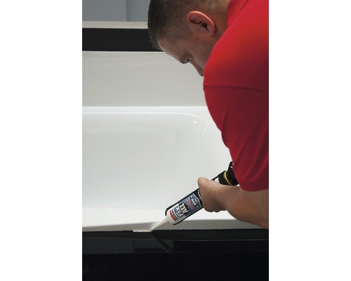 En person tätar ett badkar med tätningsmedel.