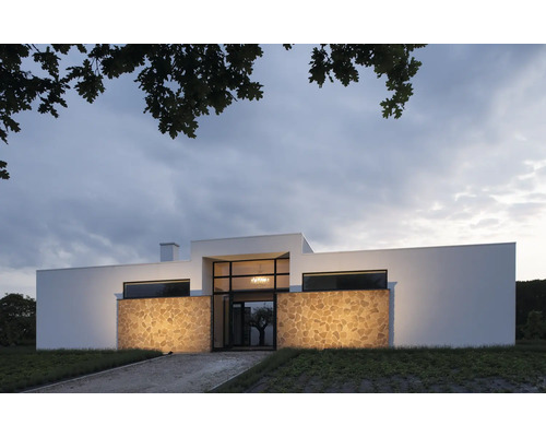 Modernt hus med naturstensfasad och stora fönster.