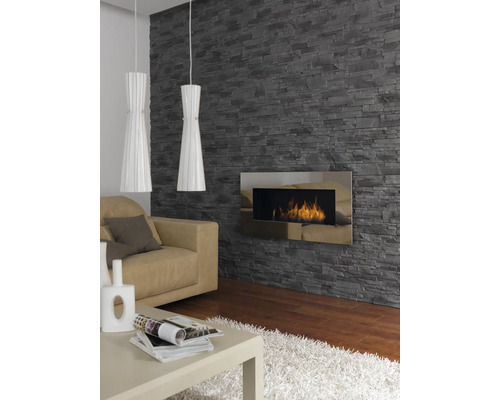 Vardagsrum med stenvägg, öppen spis, soffa, bord och två hänglampor