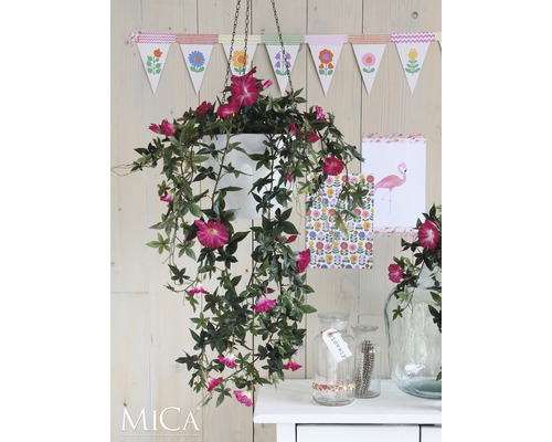 Dekorativ scen med hängande konstgjord växt i kruka och dekorationer på ett bord.