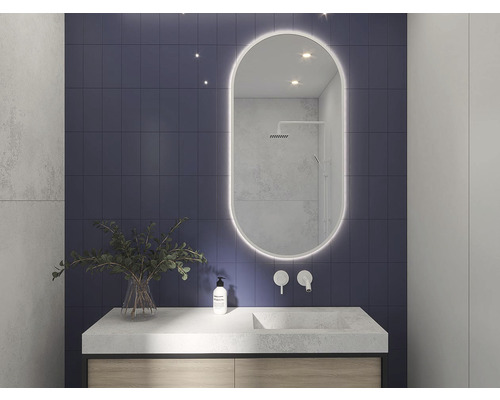 Badrum med tvättställ, spegel med belysning och blått kakel på väggen