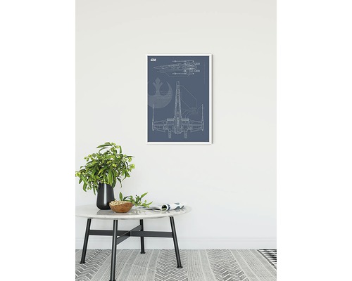 Inramad väggkonst med Star Wars X-Wing ritning på ett bord