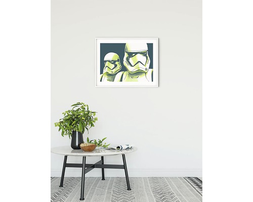 Dekorativ bild med Star Wars Stormtroopers i ram på en vägg ovanför ett bord med en vas.