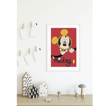 Inramad Mickey Mouse-affisch på en vägg ovanför ett bord med dekorativa element