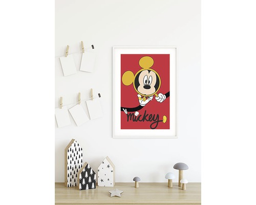 Inramad Mickey Mouse-affisch på en vägg ovanför ett bord med dekorativa element