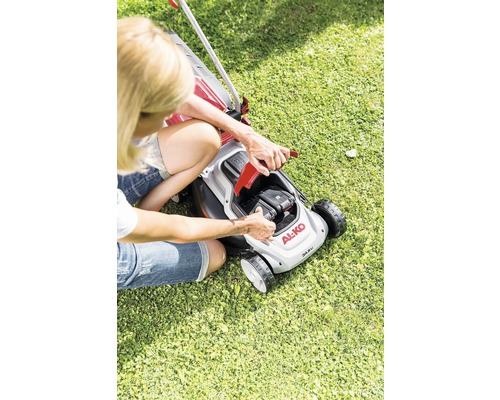 En kvinna byter batteri på en gräsklippare av märket AL-KO.
