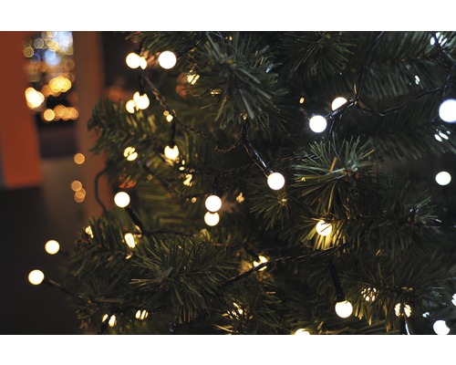 Närbild av en julgran med ljusslinga