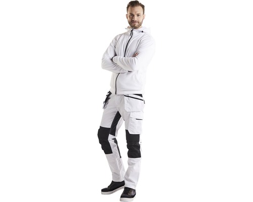 Man i arbetskläder, bestående av en jacka med huva och en arbetsbyxa med fickor