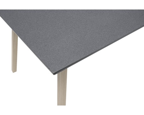 Detaljvy av ett matbord med en grå bordsskiva och ljusa bordsben.