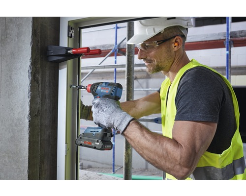 Hantverkare använder en sladdlös mutterdragare på en fönsterkarm på en byggarbetsplats.