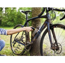 En person rengör en cykel med en högtryckstvätt utomhus.