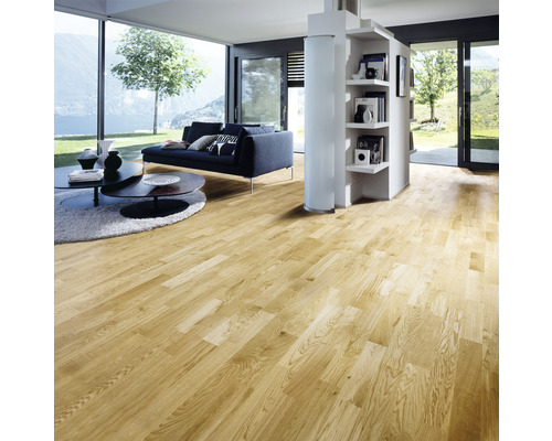 Ljust trägolv i ett vardagsrum med soffa och bokhylla.