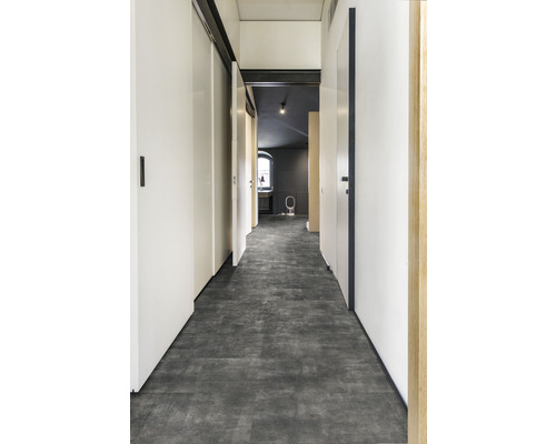 Hall med grått golvklinker, vita väggar och dörrar.