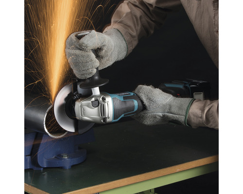 En person skär ett metallrör med en sladdlös vinkelslip och gnistor flyger.