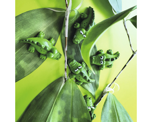 Dekorativa krokodilfigurer bland gröna blad
