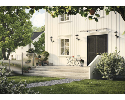 Vitt hus med entré, trädgårdsmöbler och dekorativ utomhusbelysning.