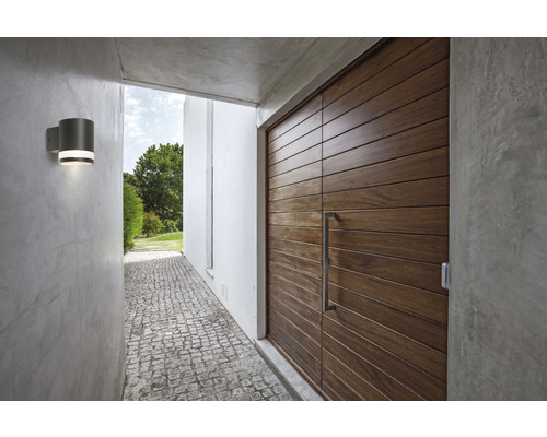 Utomhusfoto av en entré med en trädörr och en grå vägglampa